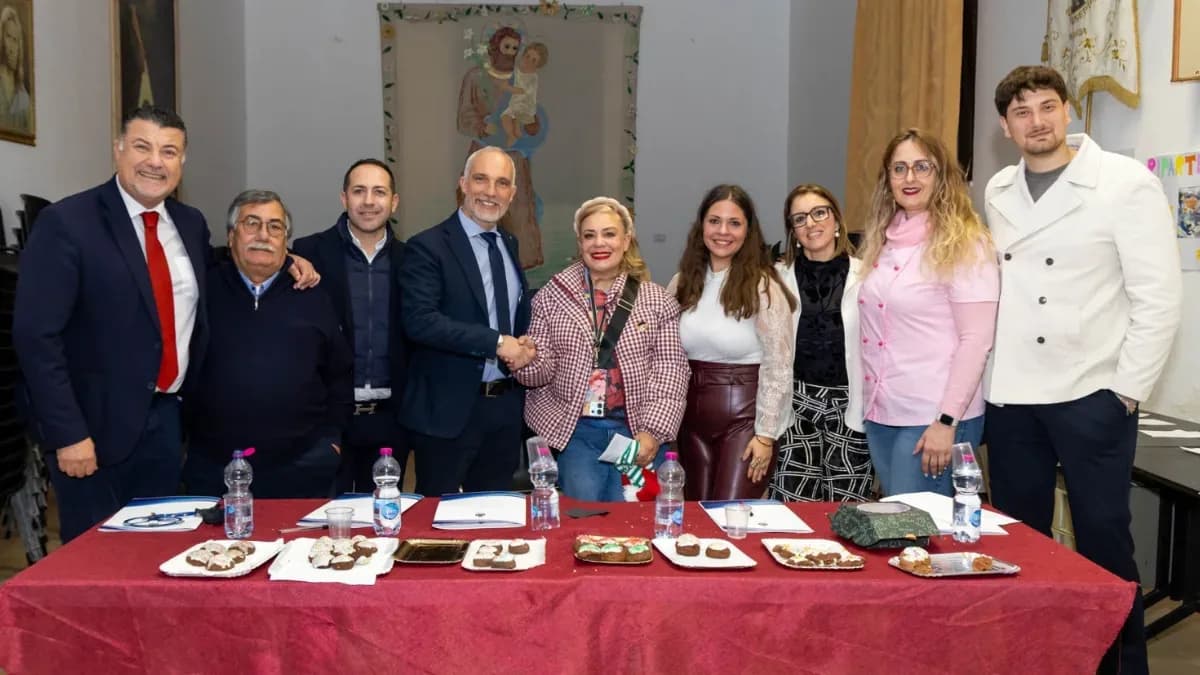 Giuria e partecipanti del concorso «Rametta Identitaria» in piedi dietro un tavolo con la tovaglia rossa e i piatti di ramette in gara